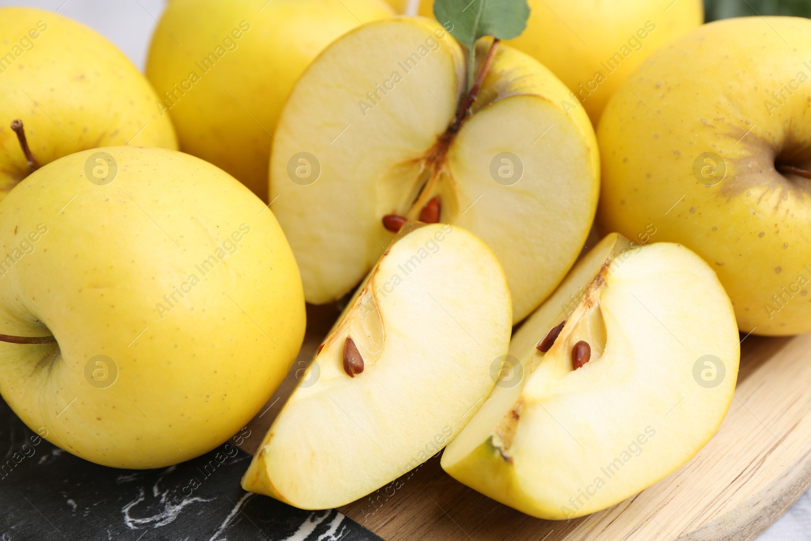 Photo of Whole and cut ripe yellow apples on table, closeup