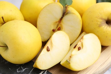 Whole and cut ripe yellow apples on table, closeup