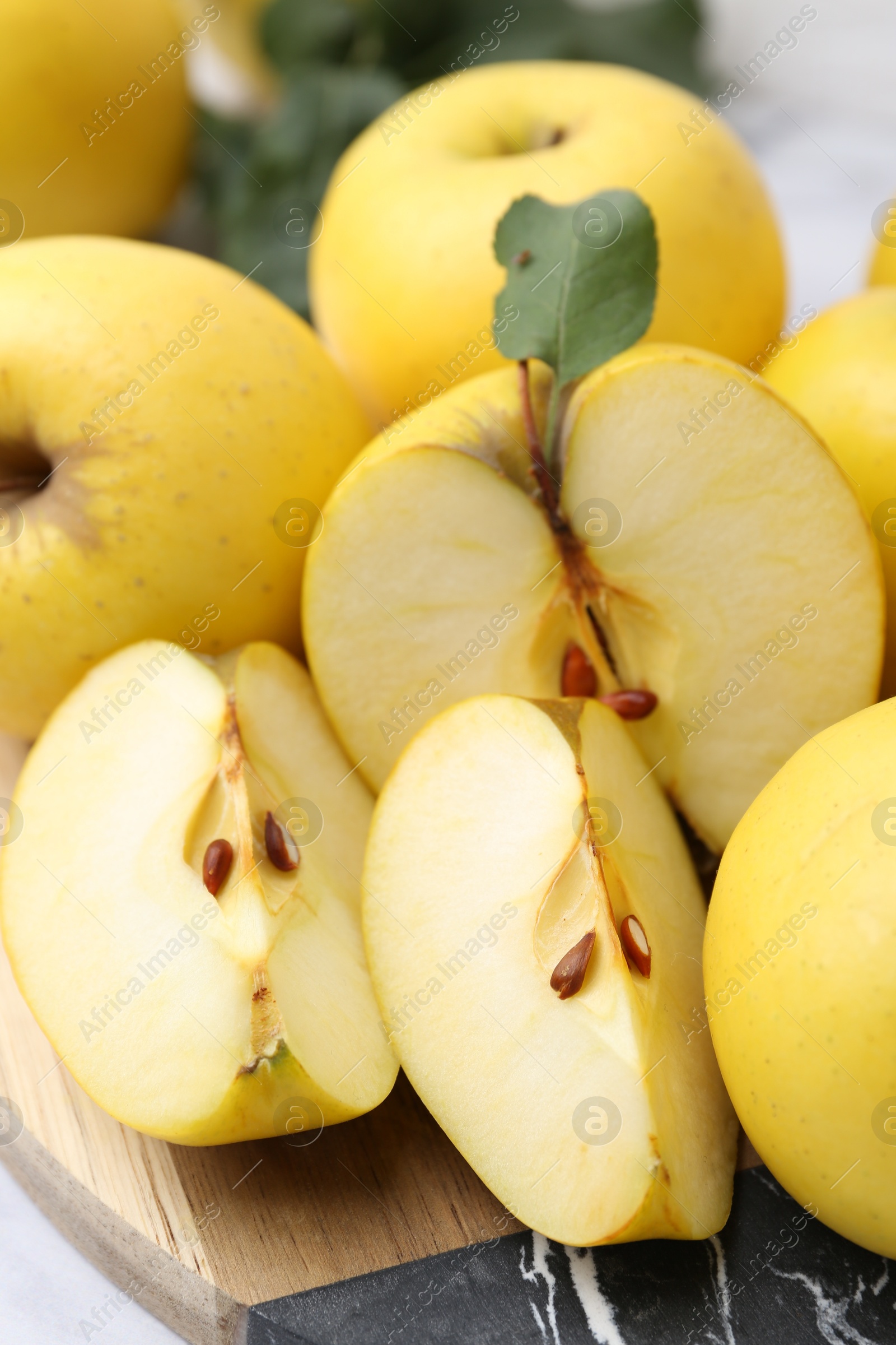 Photo of Whole and cut ripe yellow apples on table, closeup