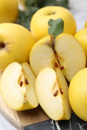 Whole and cut ripe yellow apples on table, closeup