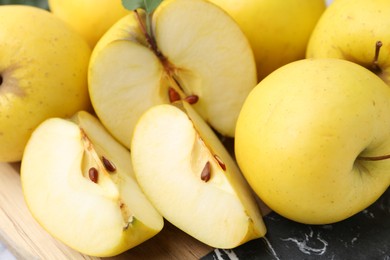 Whole and cut ripe yellow apples on table, closeup