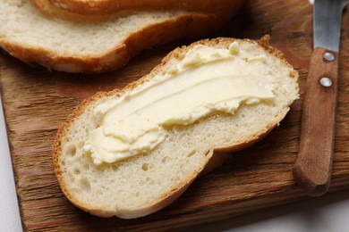 Slice of fresh bread with butter on white table, closeup