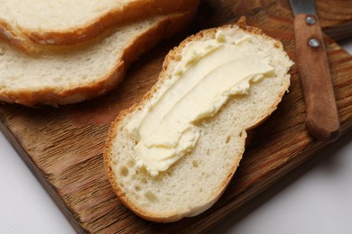 Photo of Slice of fresh bread with butter on white table, closeup