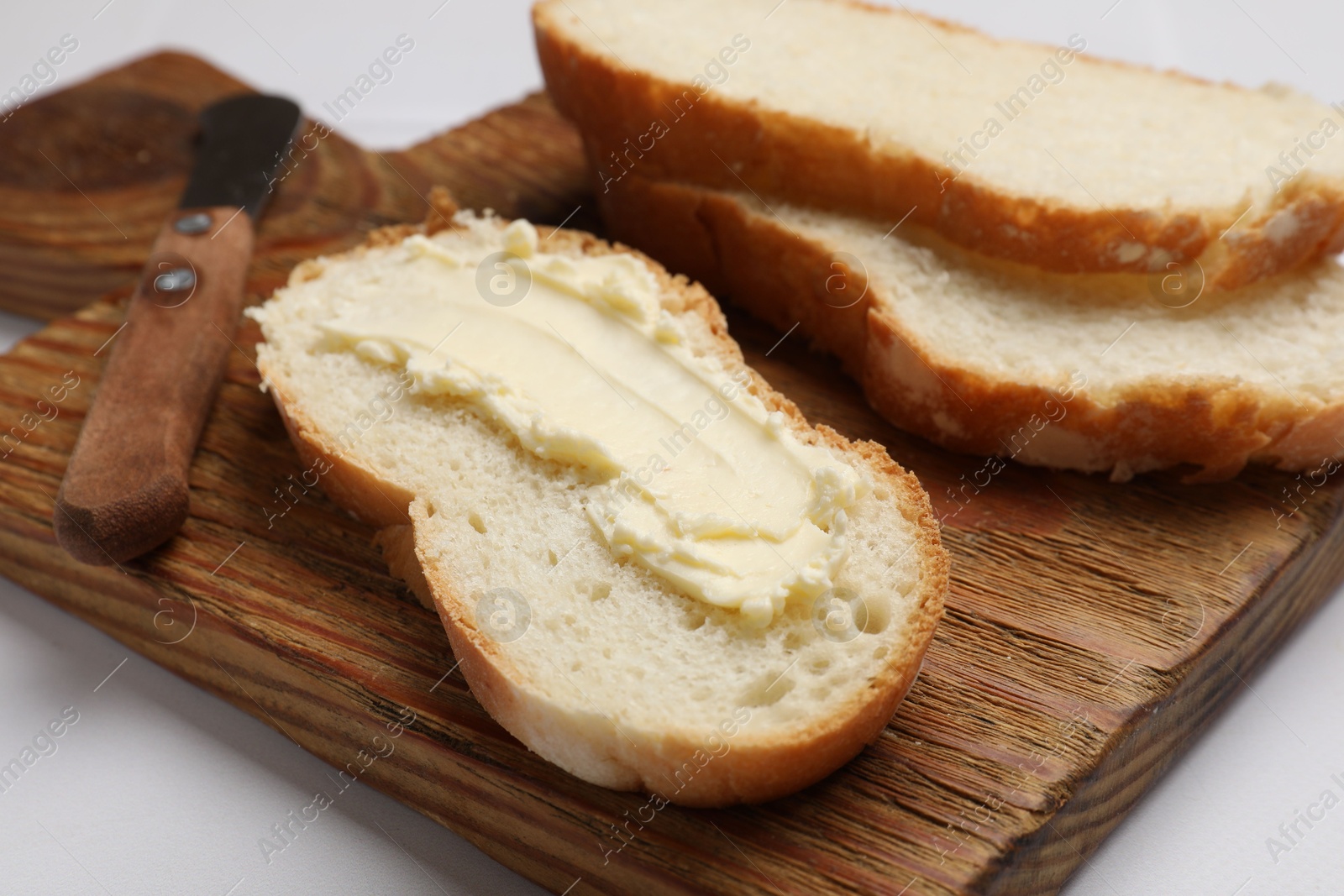 Photo of Fresh bread with butter on white table, closeup