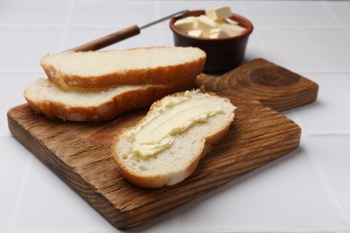 Photo of Fresh bread with butter on white tiled table, closeup