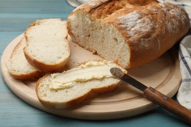 Photo of Fresh bread with butter and knife on blue wooden table, closeup