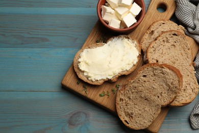 Photo of Fresh bread with butter on blue wooden table, flat lay. Space for text