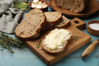 Photo of Fresh bread with butter, salt and thyme on blue wooden table