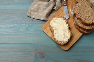 Photo of Fresh bread with butter on blue wooden table, flat lay. Space for text