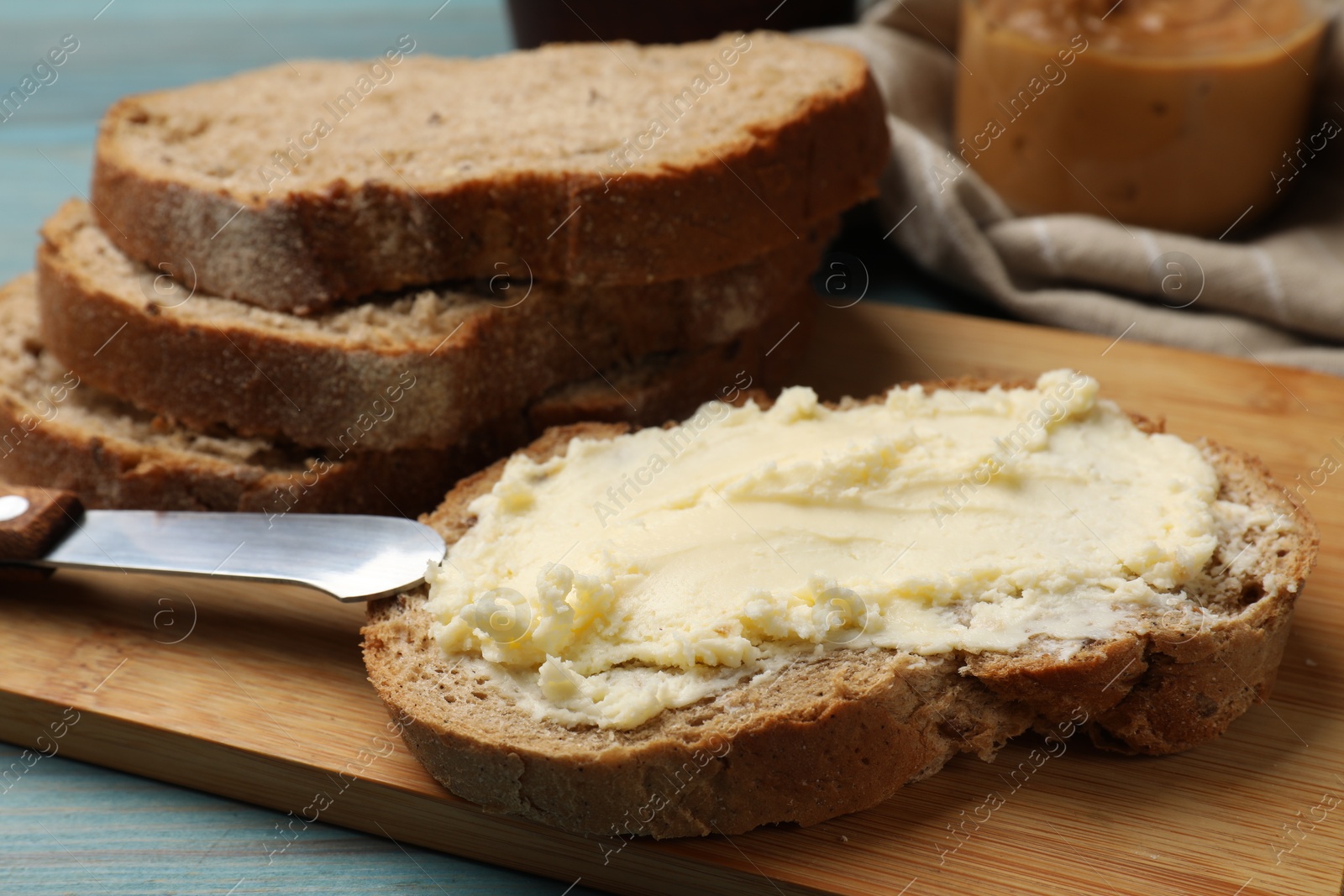 Fresh bread with butter and knife on blue wooden table, closeup Photo of Fresh bread with butter and knife on blue wooden table, closeup