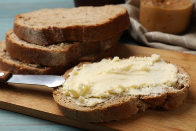 Photo of Fresh bread with butter and knife on blue wooden table, closeup