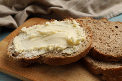 Photo of Fresh bread with butter on blue wooden table, closeup