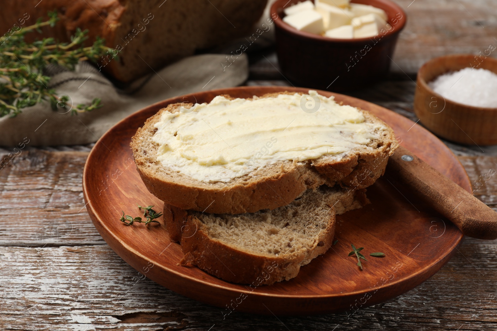 Photo of Fresh bread with butter on wooden table, closeup