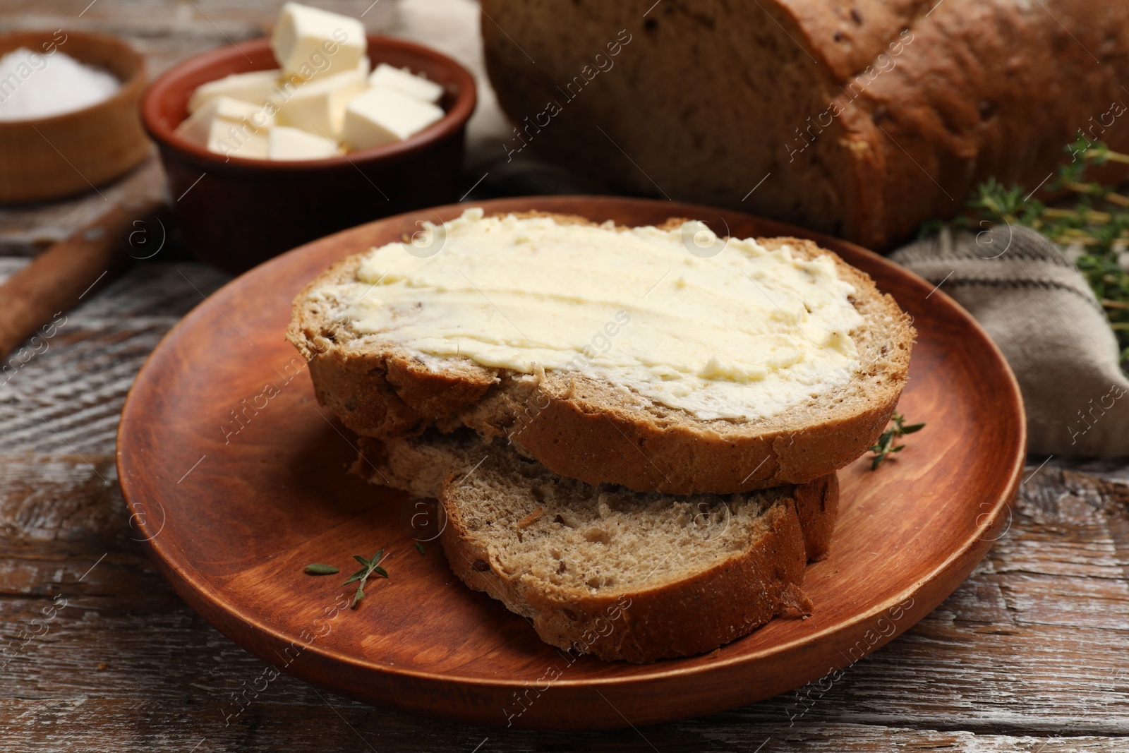 Photo of Fresh bread with butter on wooden table, closeup