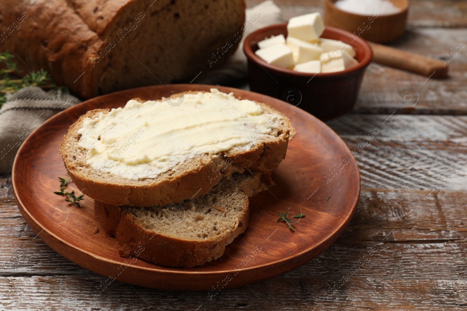 Photo of Fresh bread with butter on wooden table, closeup