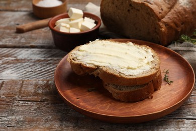 Photo of Fresh bread with butter on wooden table, closeup