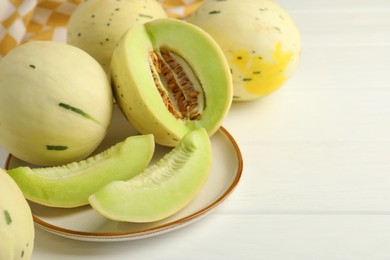 Photo of Fresh whole and cut honeydew melons on white wooden table, closeup. Space for text