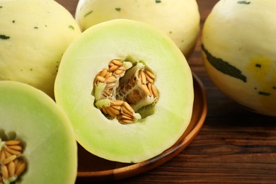 Photo of Fresh whole and cut honeydew melons on wooden table, closeup