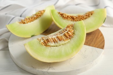 Photo of Fresh cut honeydew melon on white wooden table, closeup