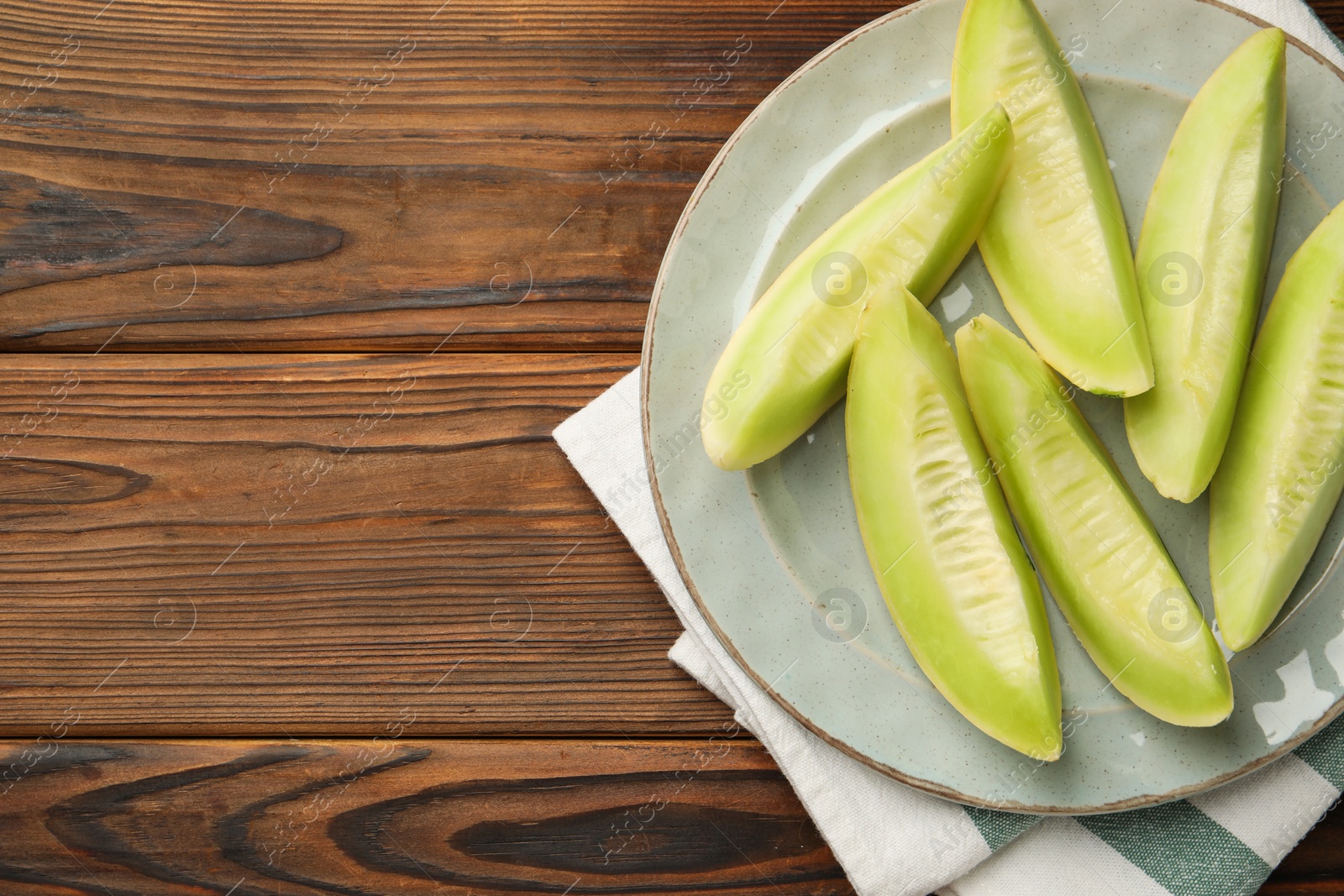 Photo of Fresh cut honeydew melon on wooden table, top view. Space for text