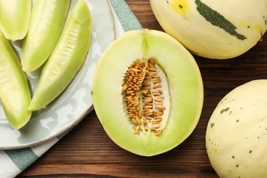 Photo of Fresh whole and cut honeydew melons on wooden table, flat lay