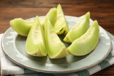 Photo of Plate with pieces of honeydew melon on wooden table, closeup