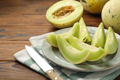 Photo of Plate with pieces of honeydew melon on wooden table, closeup