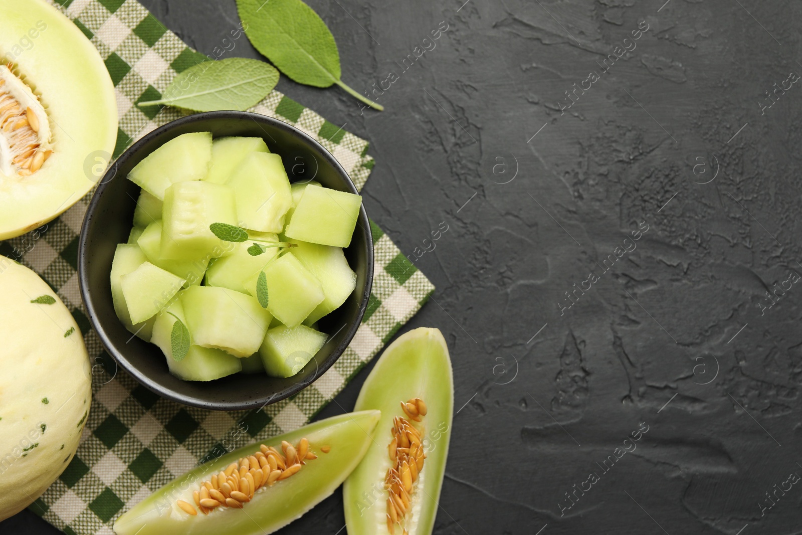 Photo of Slices of yummy melon on dark table, flat lay. Space for text