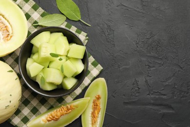 Photo of Slices of yummy melon on dark table, flat lay. Space for text