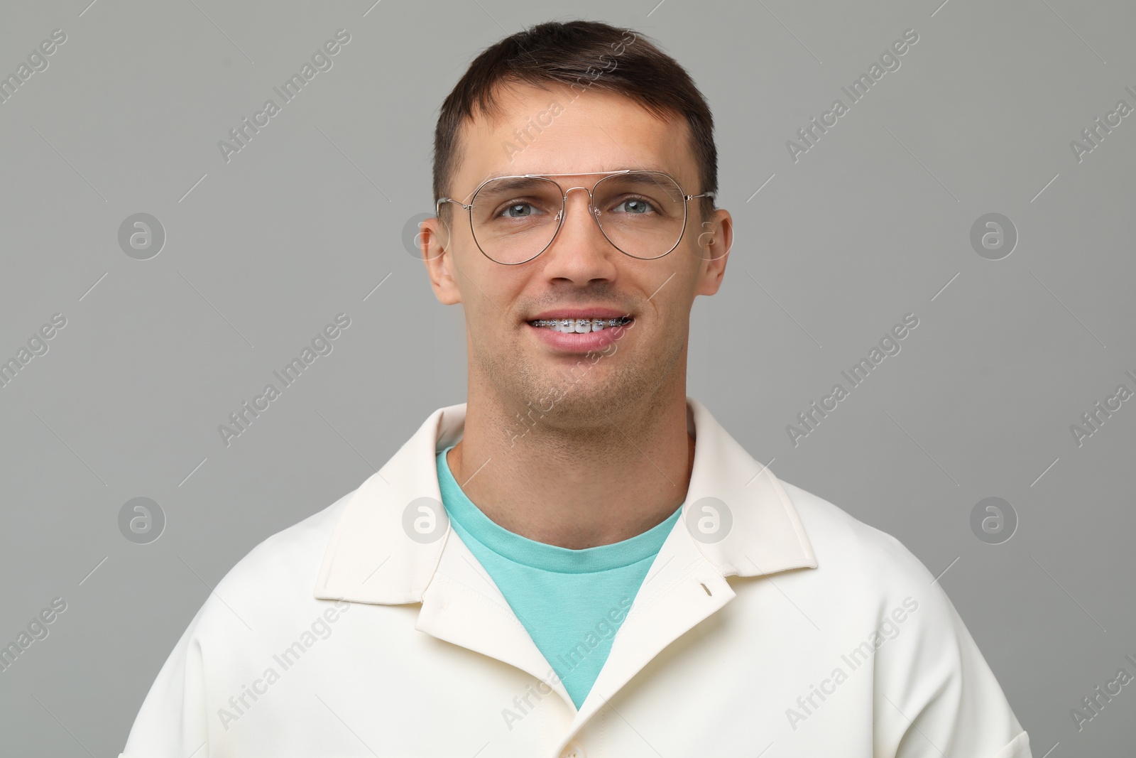 Photo of Smiling man with dental braces on grey background