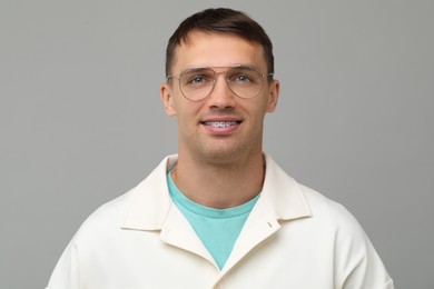 Photo of Smiling man with dental braces on grey background