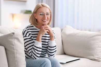 Portrait of happy middle aged woman on sofa at home, space for text