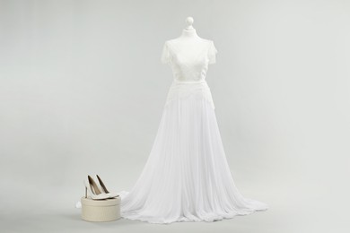 Photo of Mannequin with beautiful wedding dress and shoes on light grey background