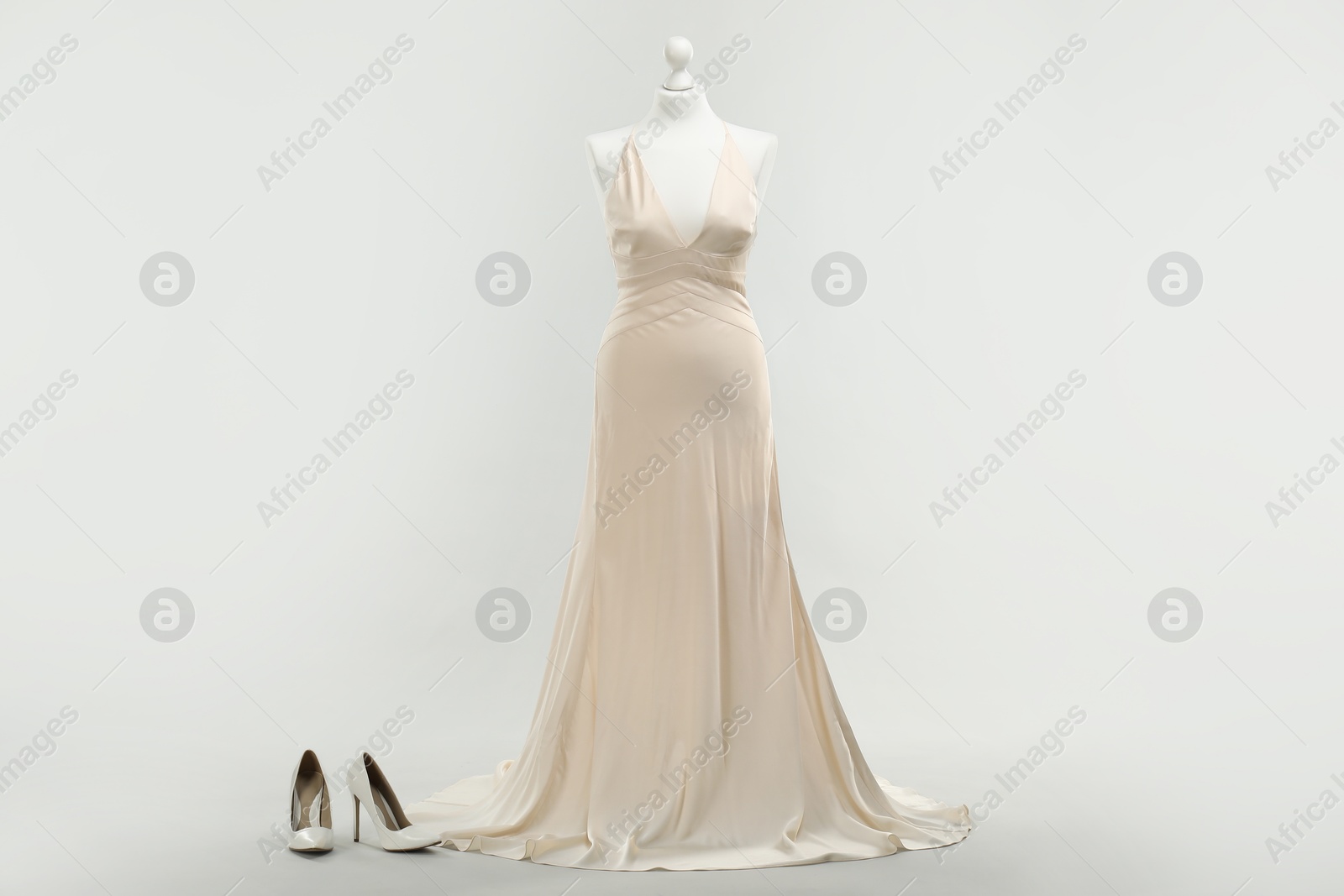 Photo of Mannequin with beautiful wedding dress and shoes on light grey background