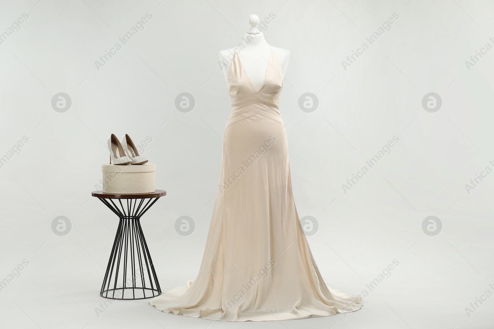 Photo of Mannequin with beautiful wedding dress and shoes on light grey background