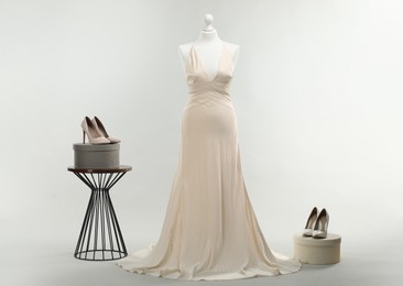 Photo of Mannequin with beautiful wedding dress and shoes on light grey background