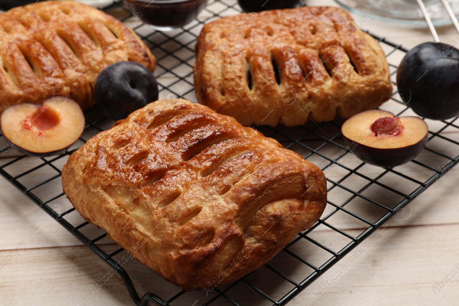 Photo of Delicious puff pastries and plums on white wooden table, closeup