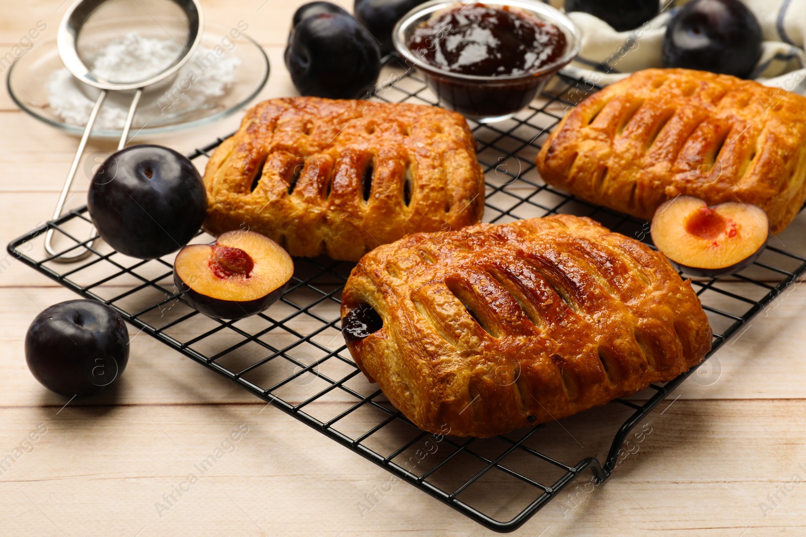 Photo of Delicious puff pastries and plums on white wooden table, closeup