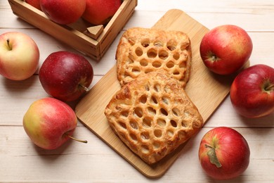 Photo of Delicious puff pastries with apples on white wooden table, flat lay