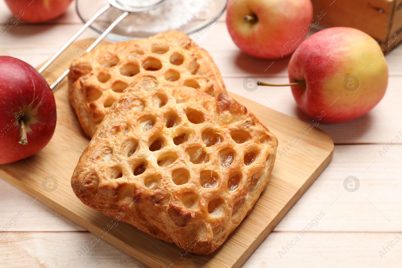 Photo of Delicious puff pastries with apples on white wooden table, closeup