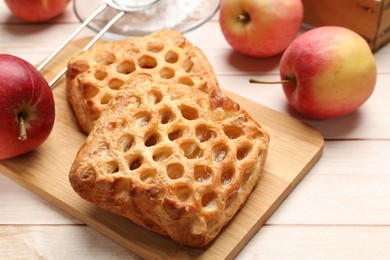 Photo of Delicious puff pastries with apples on white wooden table, closeup