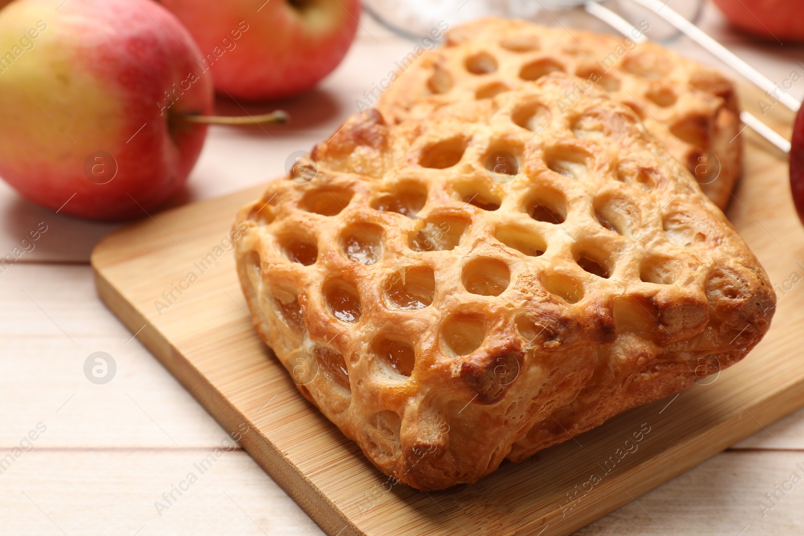 Photo of Delicious puff pastries with apples on white wooden table, closeup