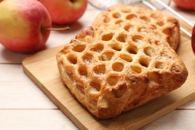 Photo of Delicious puff pastries with apples on white wooden table, closeup