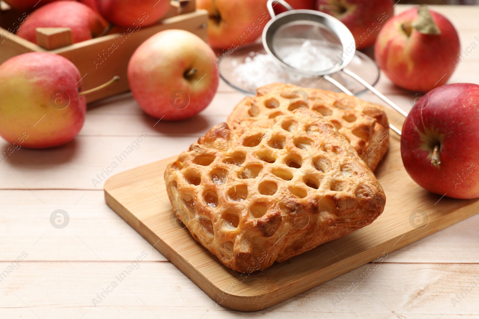 Photo of Delicious puff pastries with apples on white wooden table, closeup