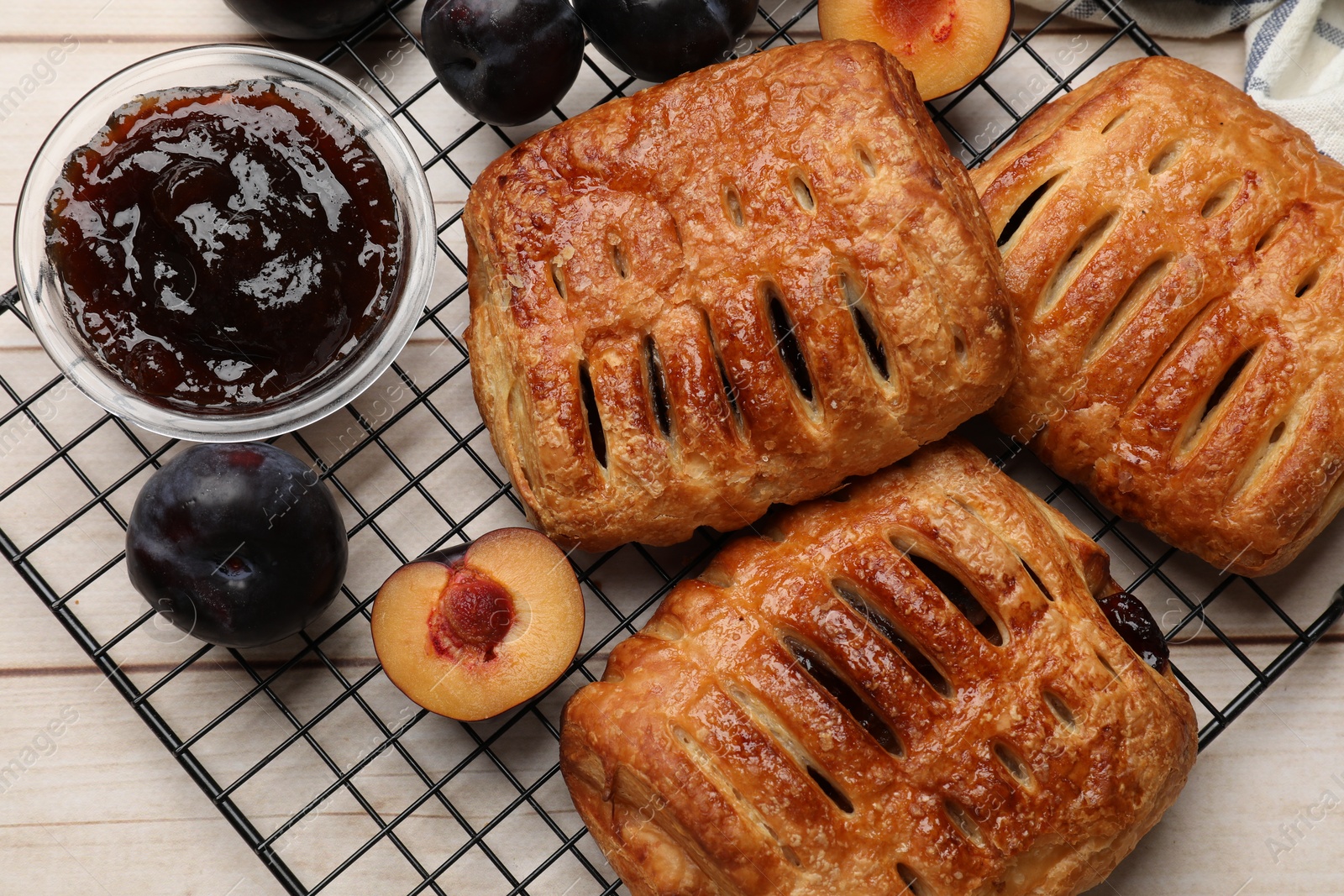 Photo of Delicious puff pastries and plums on white wooden table, flat lay