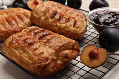 Photo of Delicious puff pastries and plums on white wooden table, closeup