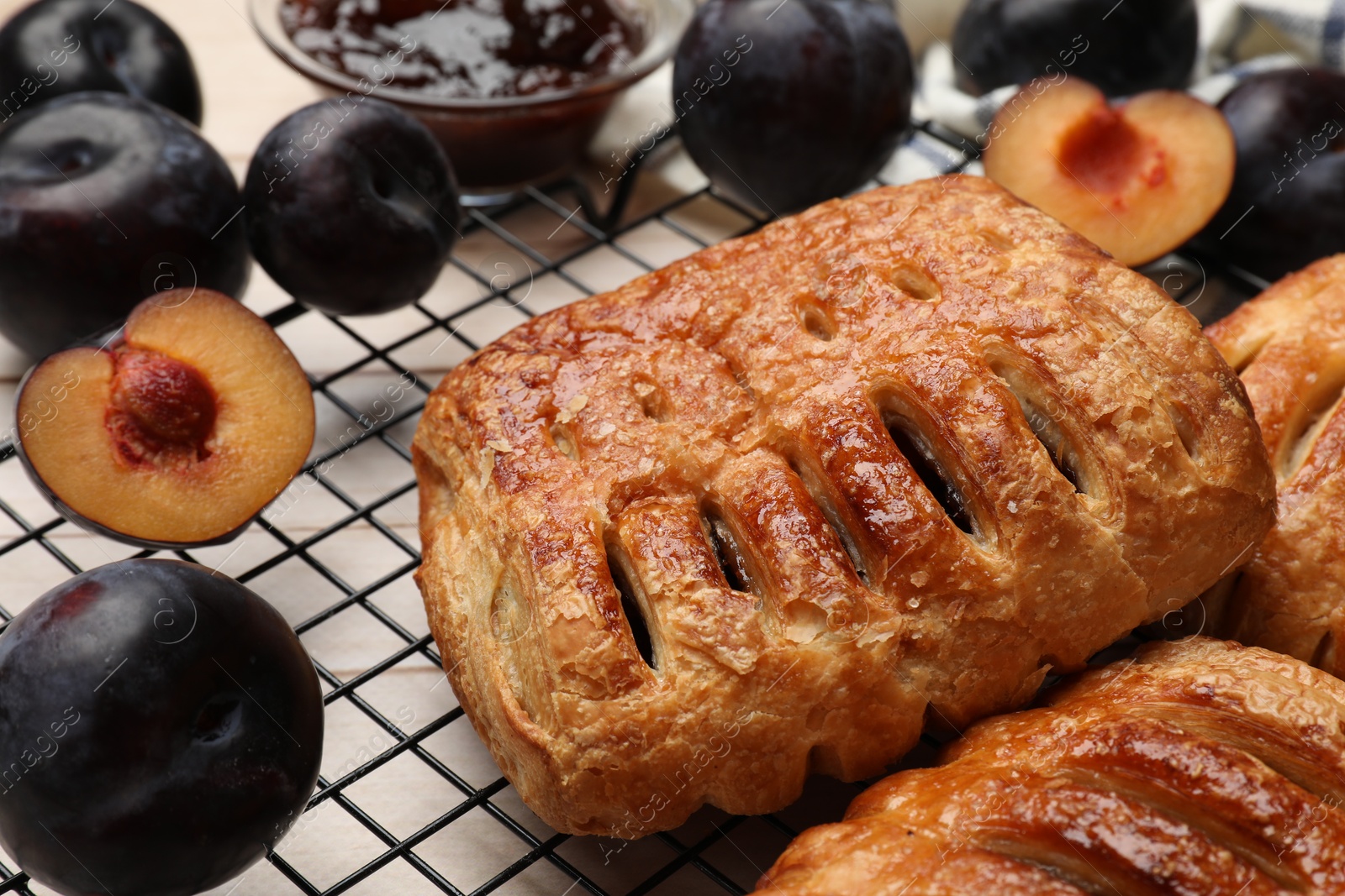 Photo of Delicious puff pastries and plums on white wooden table, closeup