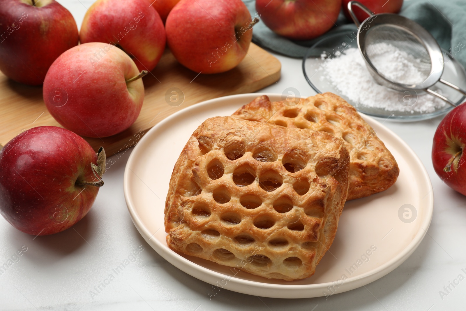 Photo of Delicious puff pastries with apples on white wooden table, closeup