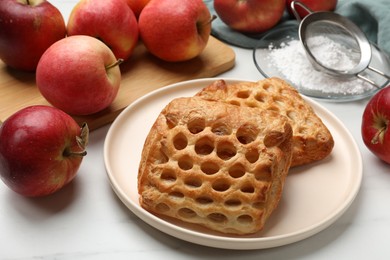 Photo of Delicious puff pastries with apples on white wooden table, closeup