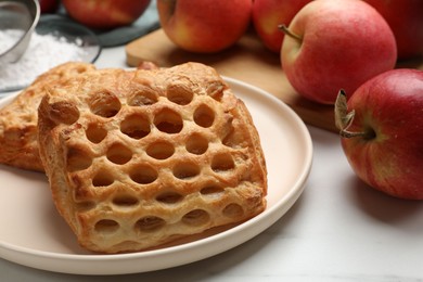 Photo of Delicious puff pastries with apples on white wooden table, closeup